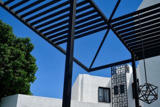 Pergola en aluminium au-dessus d'une terrasse urbaine avec fauteuils vintage